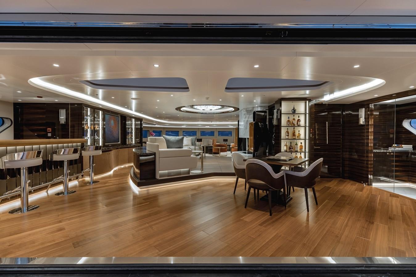 a room with a wood floor and a couch and a table with chairs aboard VICTORIOUS Yacht for Charter