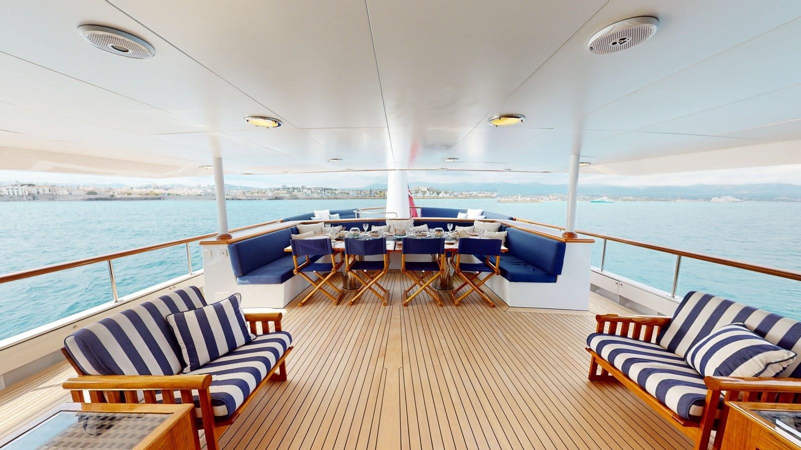a deck with chairs and tables on it by the water aboard WILAMINA Yacht for Sale