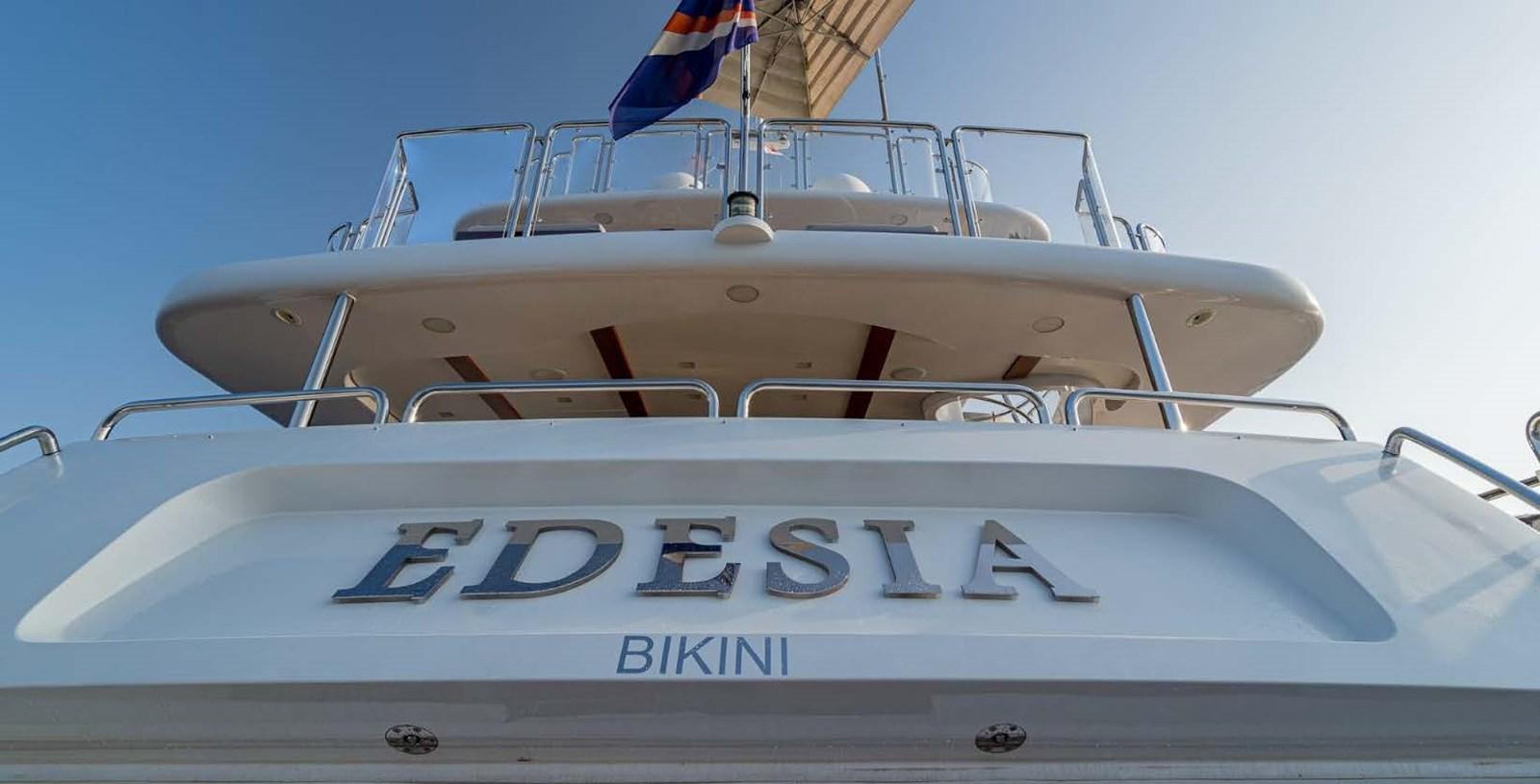 a white boat with a blue and white striped front aboard EDESIA Yacht for Charter