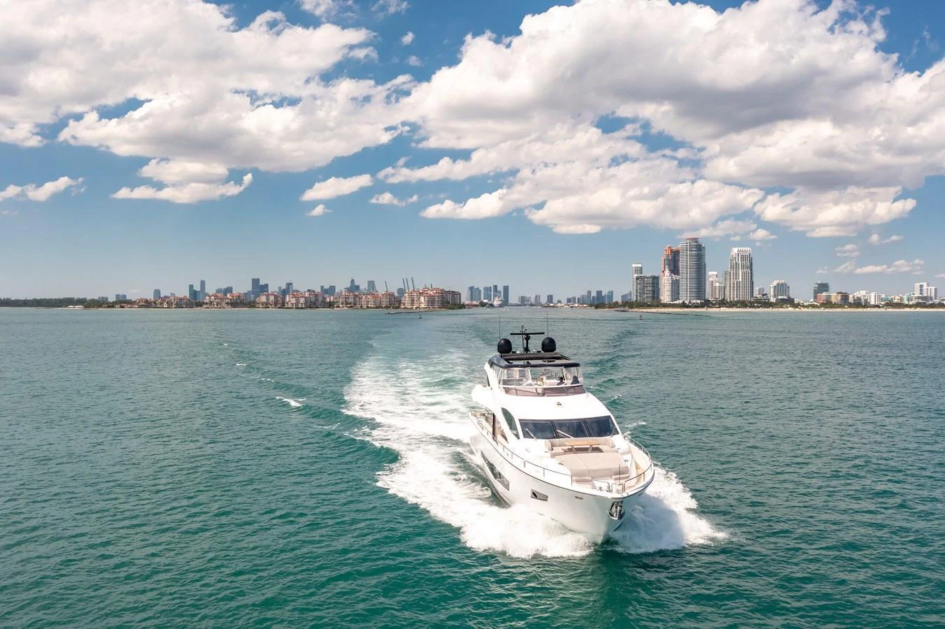 A sleek yacht cruises through calm waters with a city skyline in the background. aboard SUNSEEKER Yacht for Sale