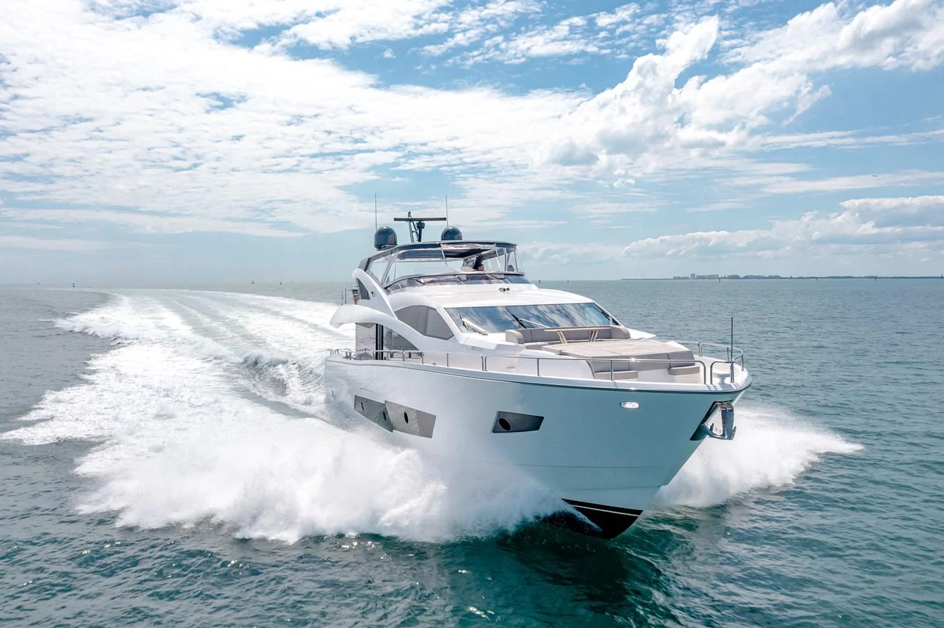 A sleek, modern yacht cruises swiftly across the open water under a bright, clear sky. aboard SUNSEEKER Yacht for Sale