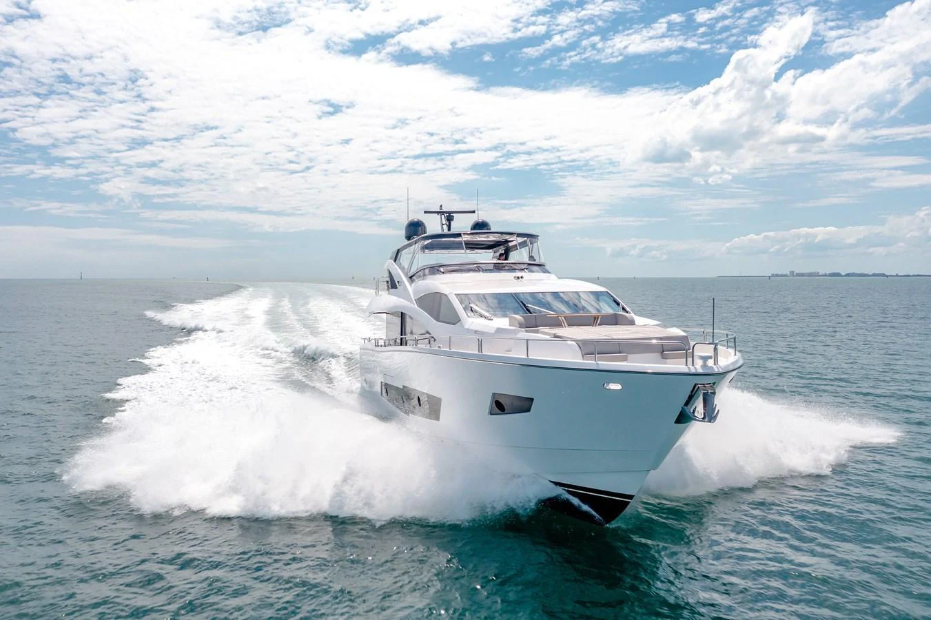 A sleek yacht cruises swiftly across the open sea under a bright, partly cloudy sky. aboard SUNSEEKER Yacht for Sale