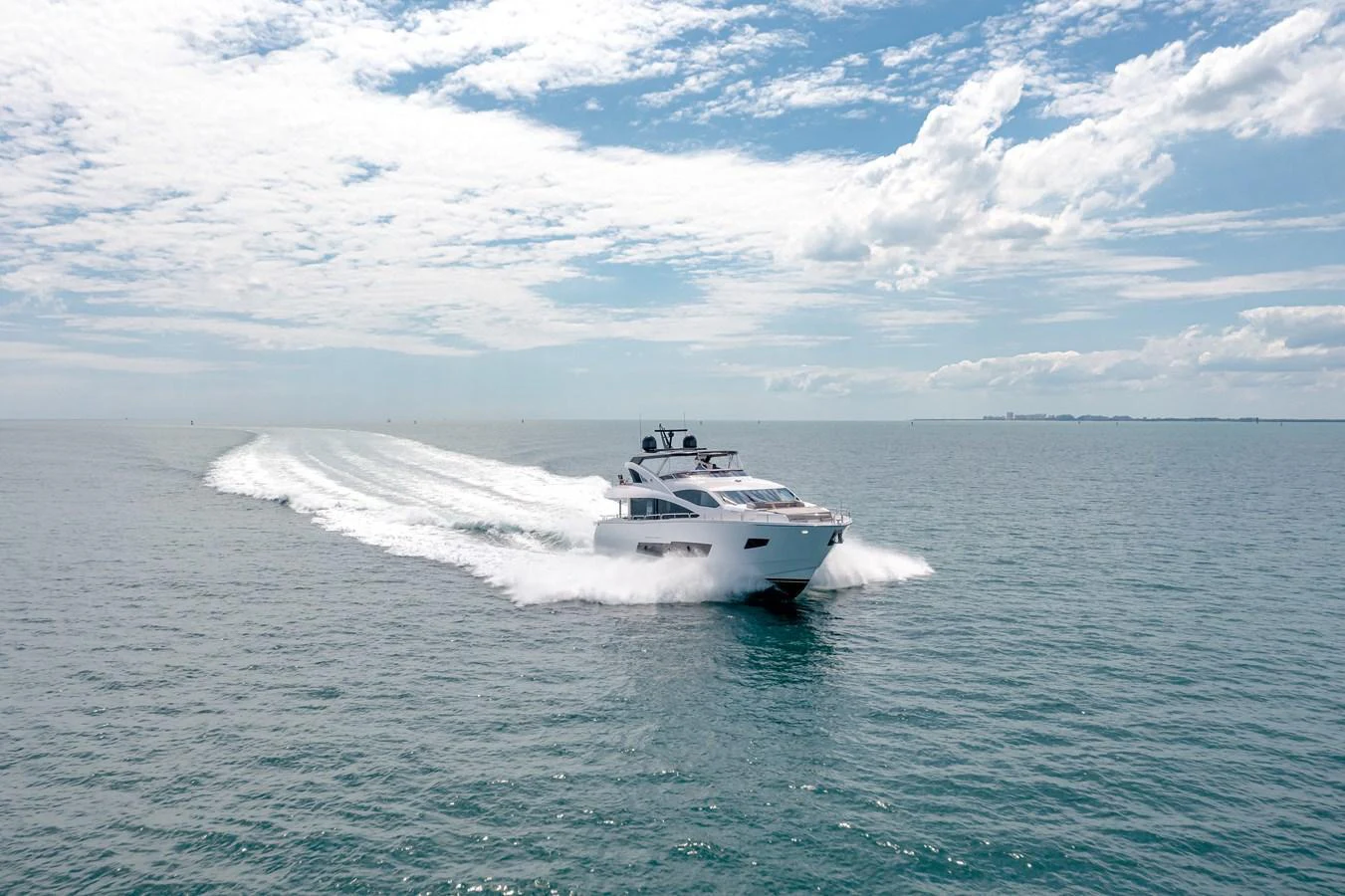 A sleek yacht glides swiftly across the open sea under a bright, partly cloudy sky. aboard SUNSEEKER Yacht for Sale