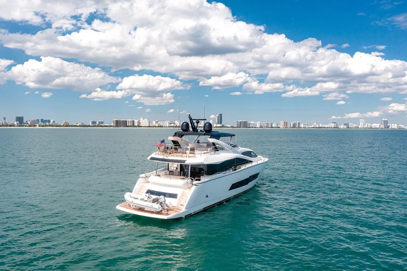 A sleek yacht cruises on calm waters with a city skyline in the background. aboard SUNSEEKER Yacht for Sale
