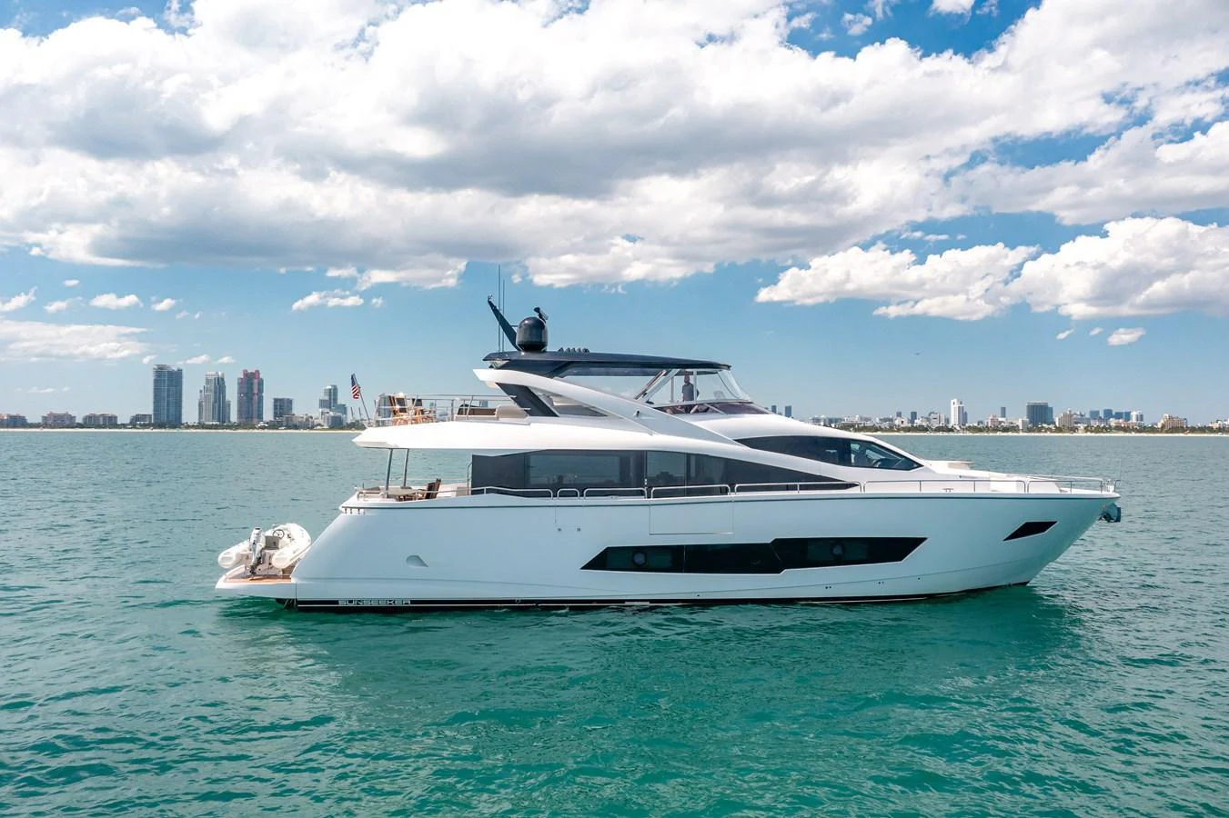 A sleek and modern yacht glides gracefully on calm waters with a cityscape in the background. aboard SUNSEEKER Yacht for Sale