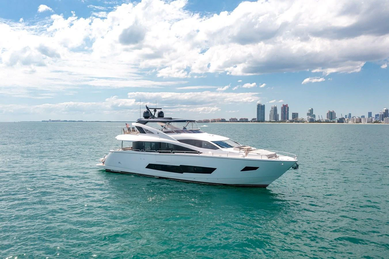 A sleek and modern yacht cruising on calm waters with a cityscape in the background. aboard SUNSEEKER Yacht for Sale