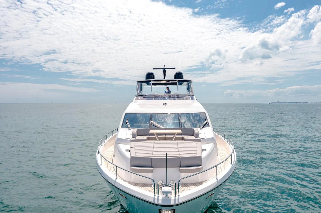 A sleek yacht is cruising on calm waters under a bright, partly cloudy sky. aboard SUNSEEKER Yacht for Sale