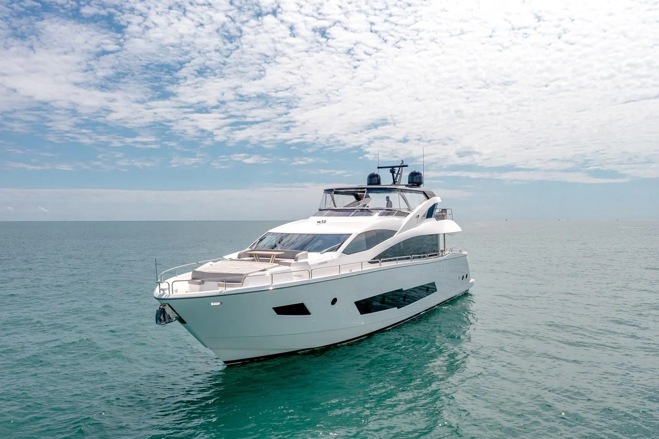 A sleek and modern yacht glides gracefully on calm waters under a partly cloudy sky. aboard SUNSEEKER Yacht for Sale