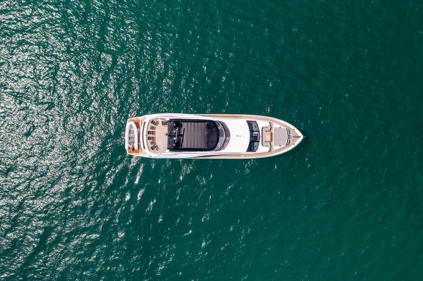 A sleek yacht cruises through clear, turquoise waters, viewed from above. aboard SUNSEEKER Yacht for Sale