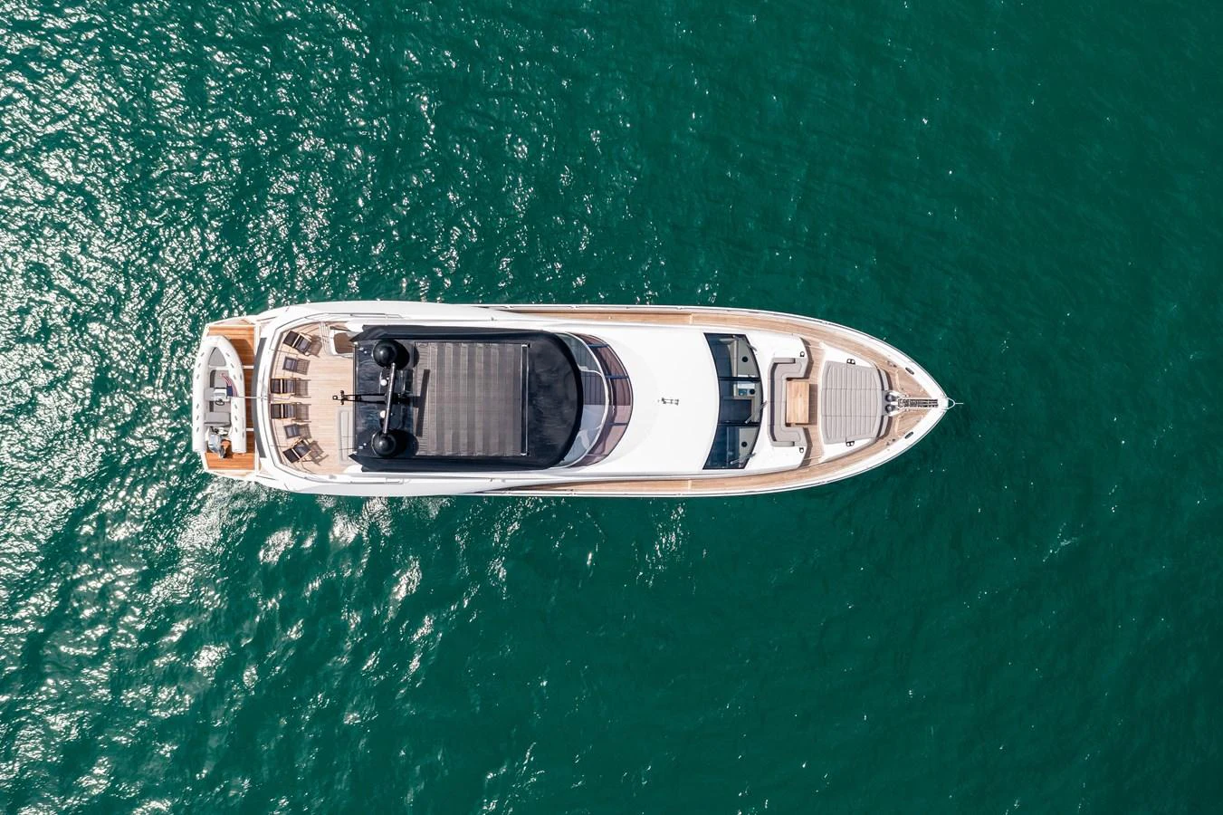 An aerial view of a sleek yacht cruising through clear, green waters. aboard SUNSEEKER Yacht for Sale