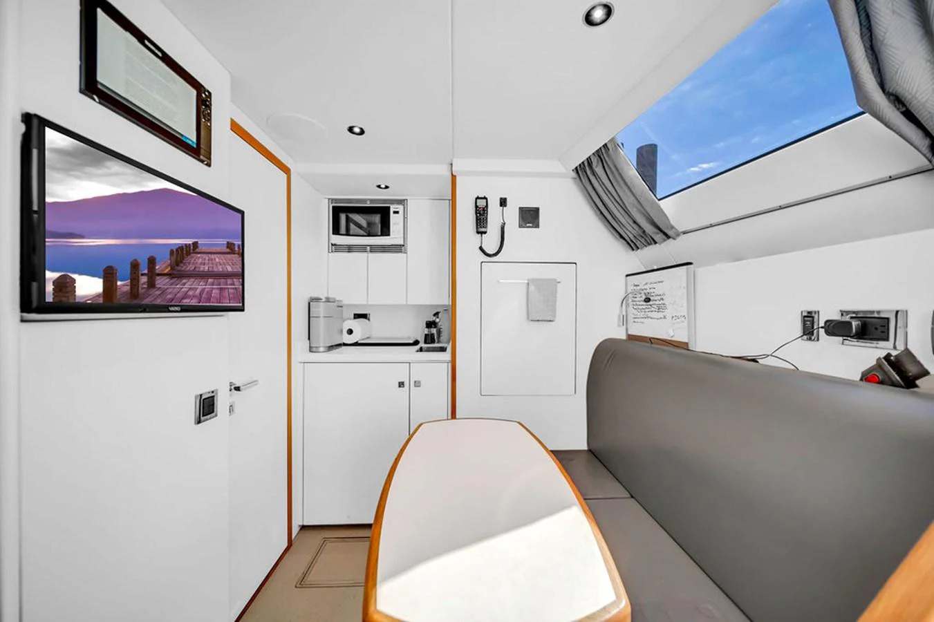 The yacht's saloon features a cozy seating area with a table, a television, and ample natural light from the skylight. aboard SUNSEEKER Yacht for Sale