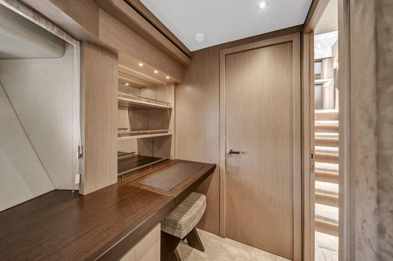 This image showcases a sleek and modern interior space with a desk and shelving, leading up to a staircase. aboard SUNSEEKER Yacht for Sale