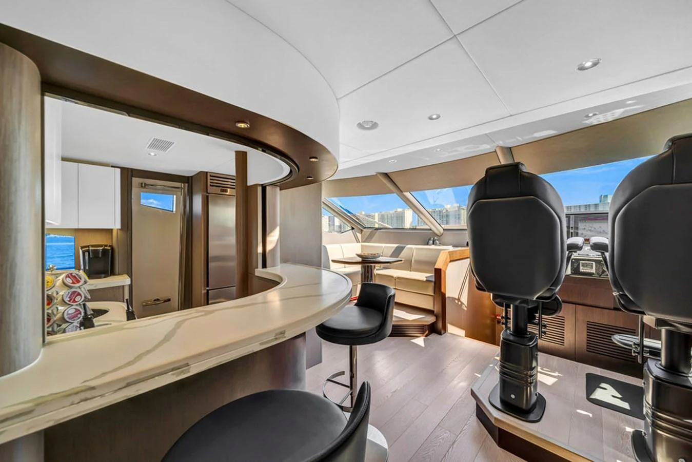 The helm area features modern seating and a sleek, curved bar with a view of the water through large windows. aboard SUNSEEKER Yacht for Sale