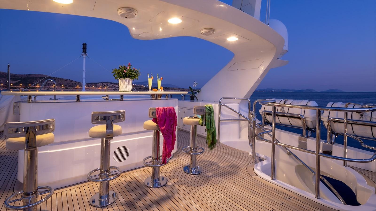 a deck with a large pool and a deck with chairs and tables aboard RIVA I Yacht for Sale