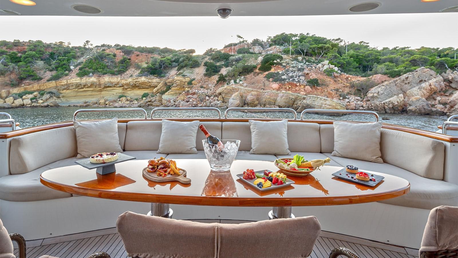 a white couch with a table and chairs in front of a large window aboard RIVA I Yacht for Sale