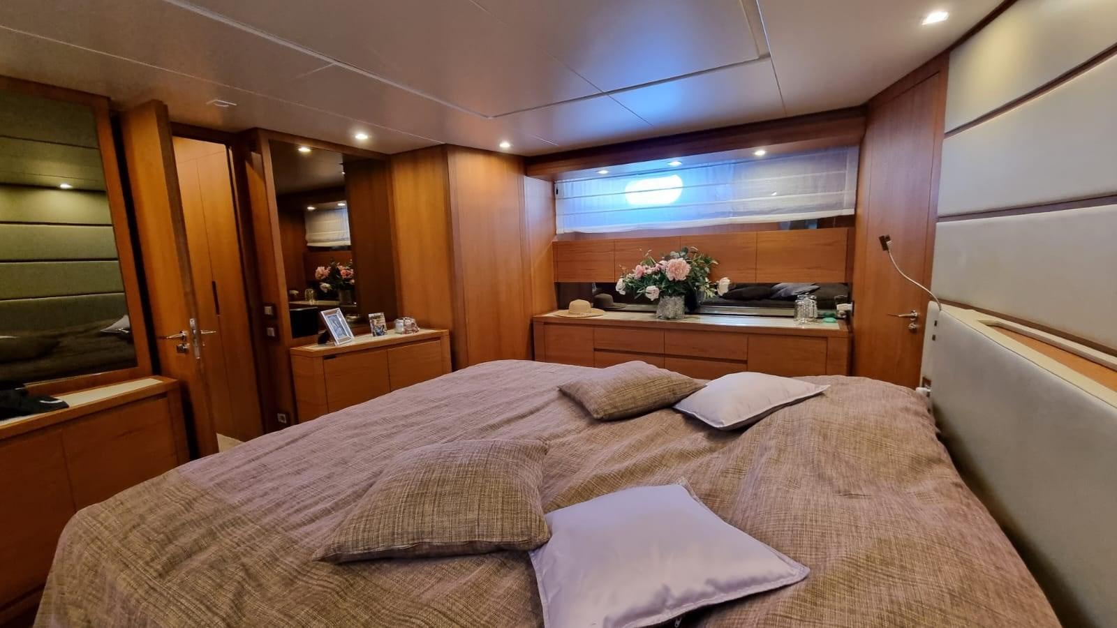 a bed with a white sheet and pillows in a room with wood cabinets aboard DOUBLE B Yacht for Sale