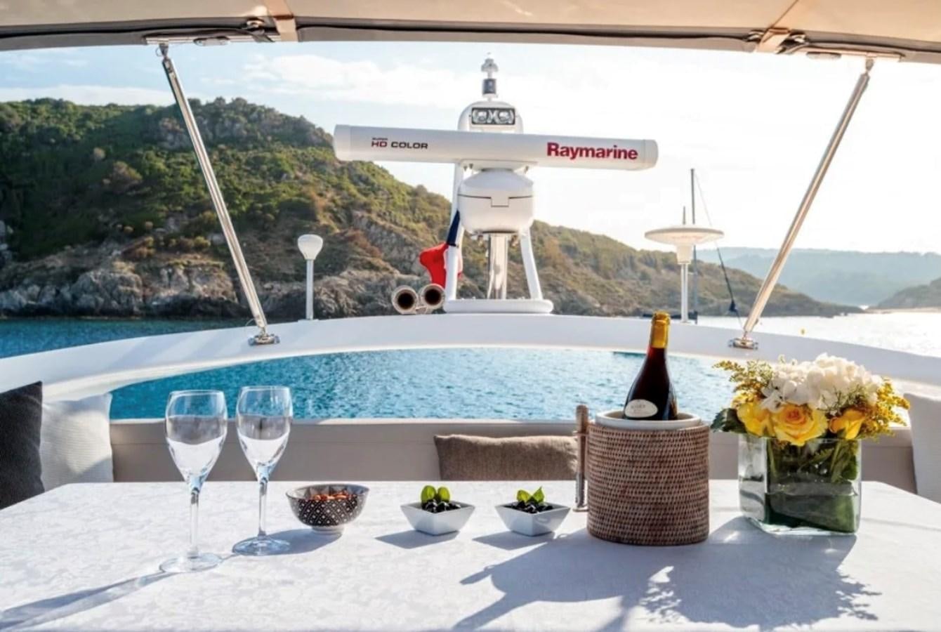 a table with wine glasses and a bottle of wine on it aboard PRINCESS S72 Yacht for Sale