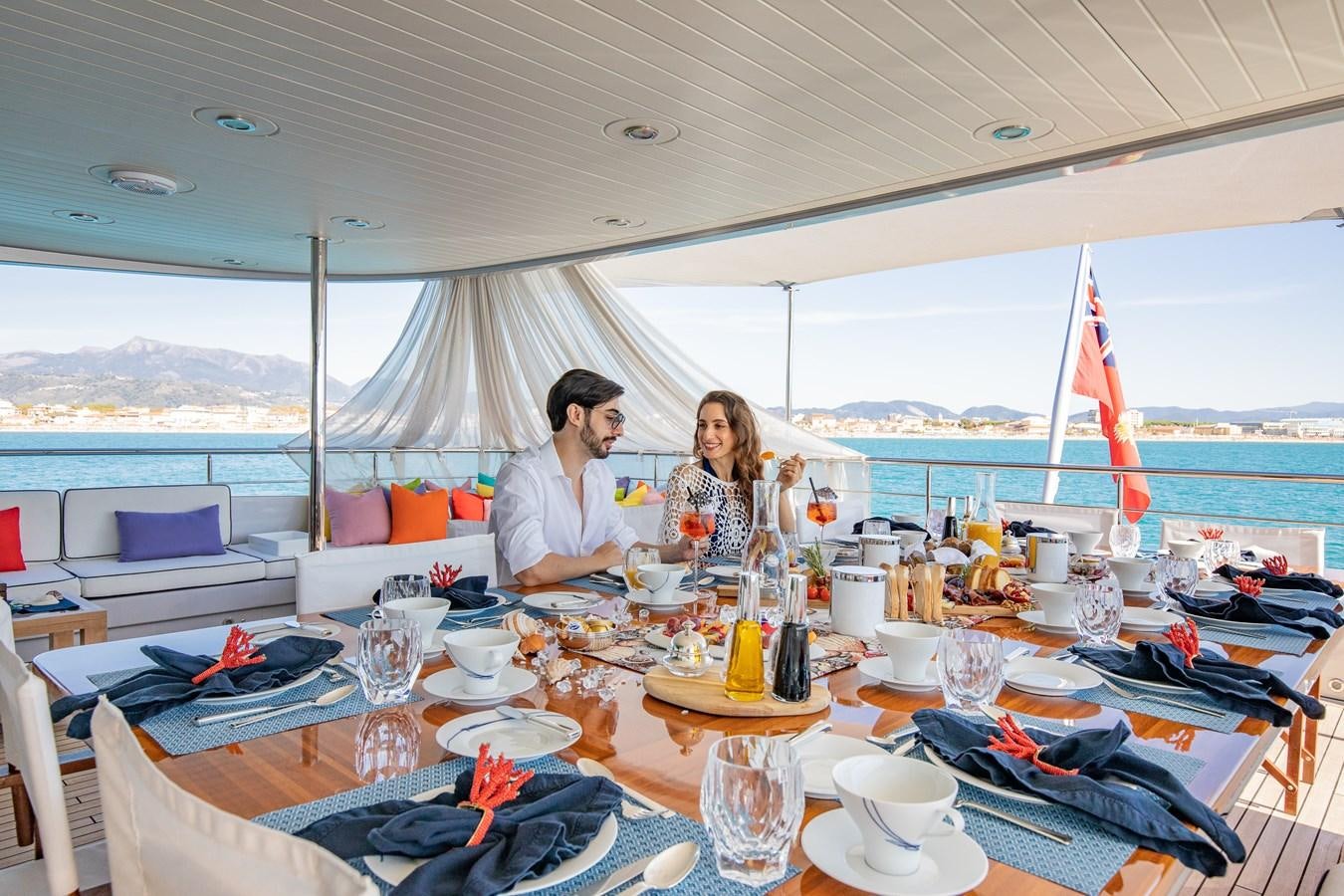a group of people sitting at a table with food and drinks aboard HATT MILL Yacht for Sale