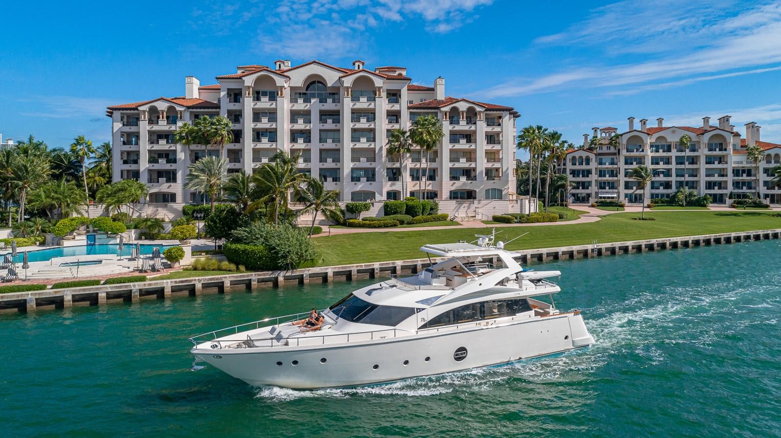 a white boat on water with Fisher Island in the background aboard THERAPY Yacht for Sale