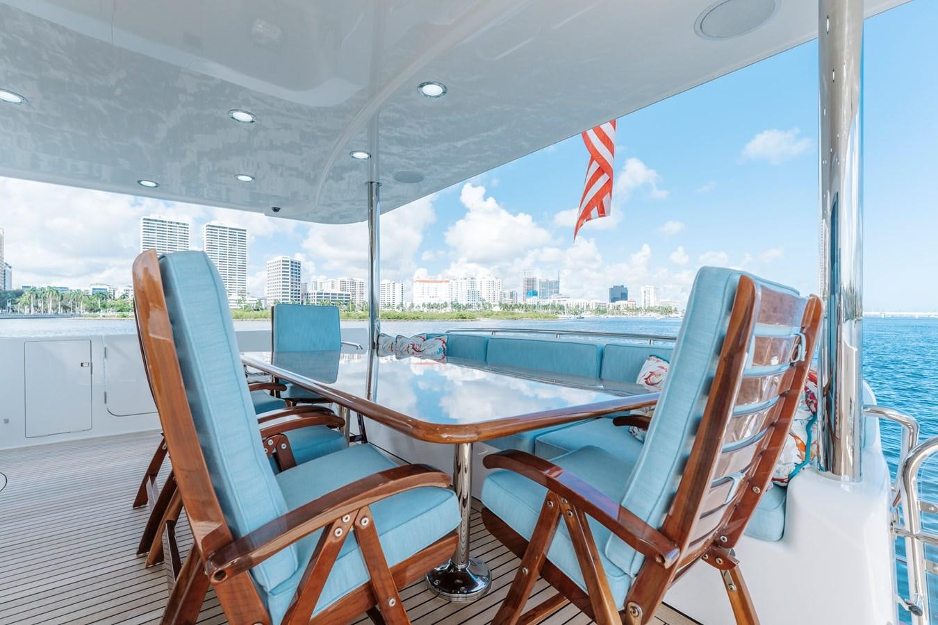 a deck with a table chairs and a flag on it aboard FULLY OCCUPIED Yacht for Sale