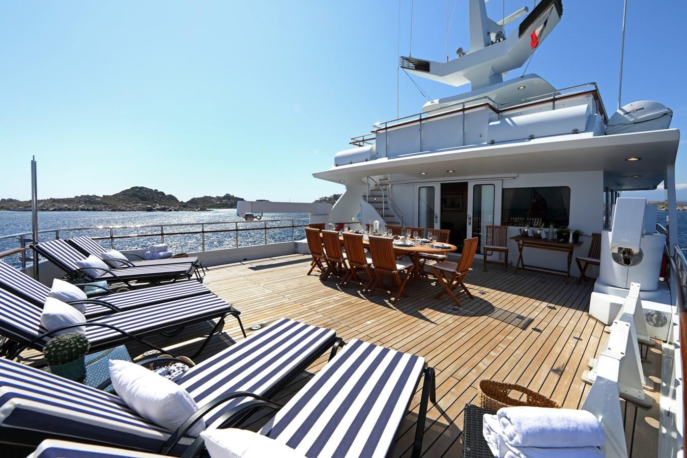 a deck with a table and chairs on it aboard L'ALBATROS Yacht for Charter