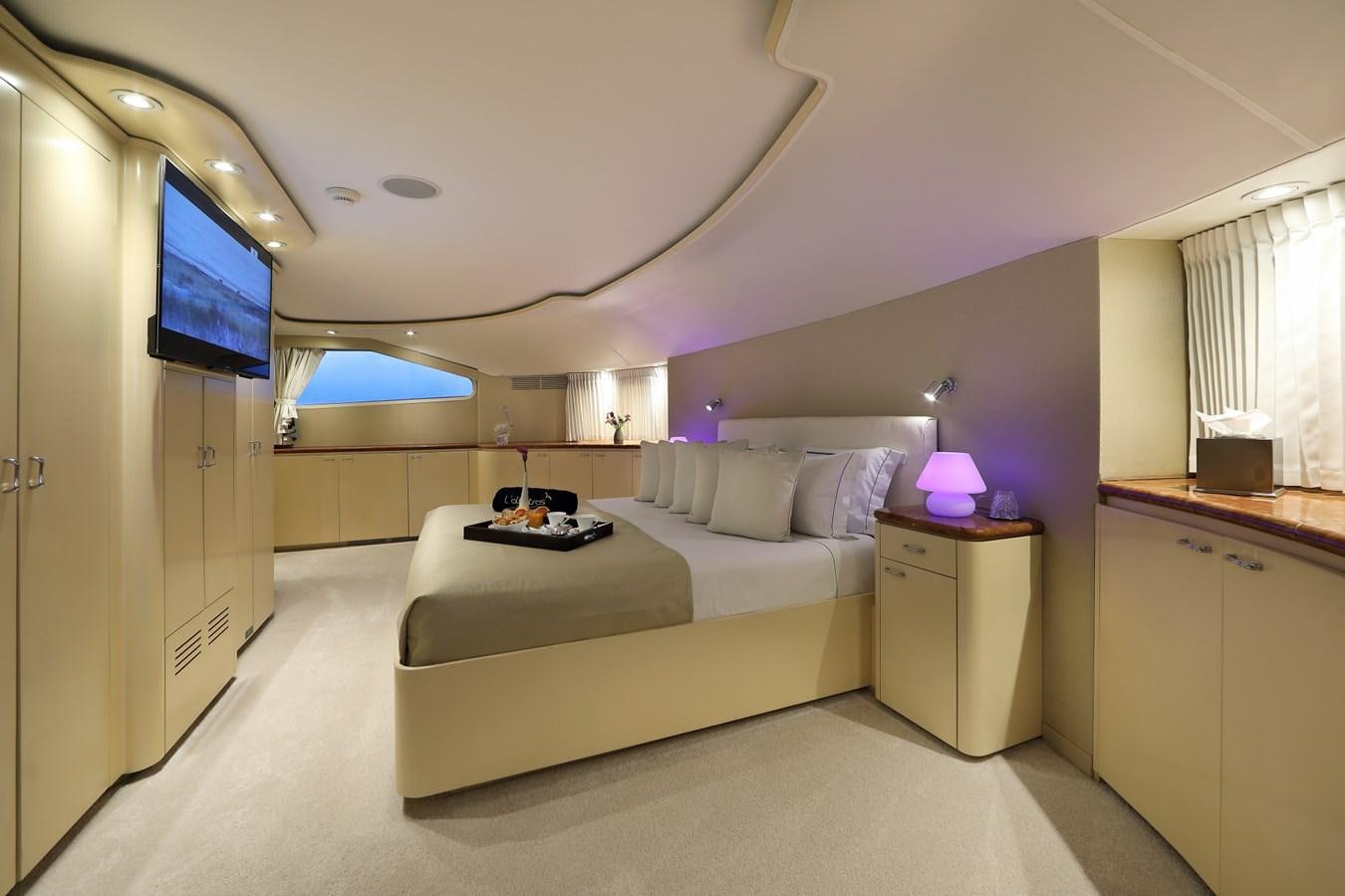 a bedroom with a bed and a tv on the wall aboard L'ALBATROS Yacht for Charter