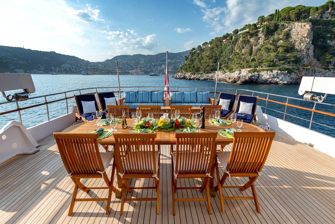 a table set for a meal on a deck overlooking a large body of water aboard L'ALBATROS Yacht for Sale