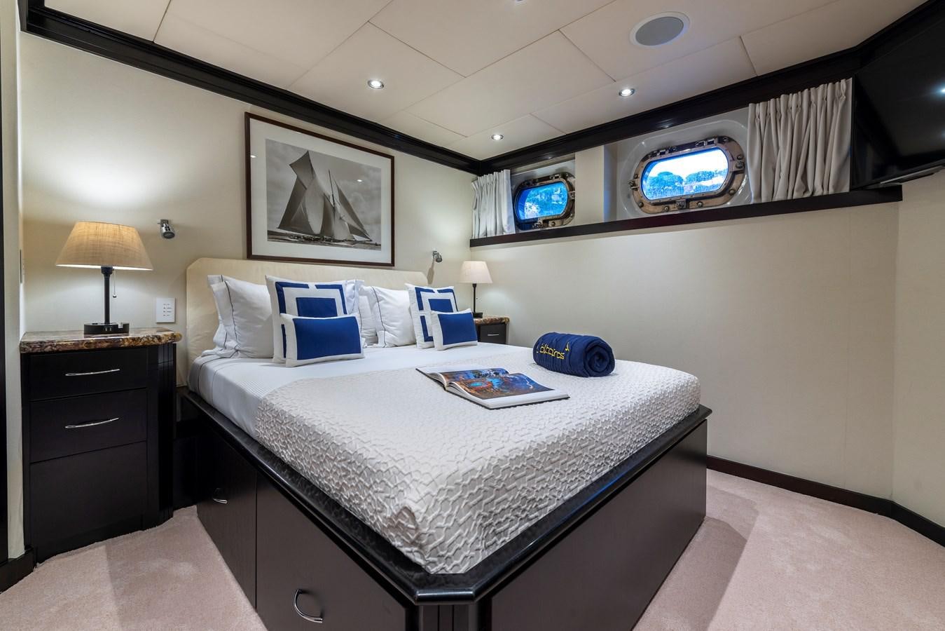 a bed with a white sheet and a blue pillow on it aboard L'ALBATROS Yacht for Sale
