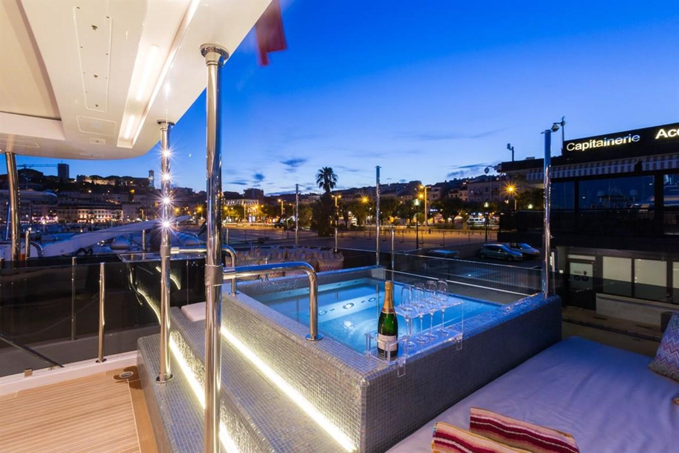 a glass bottle on a table by a pool aboard GALA Yacht for Sale