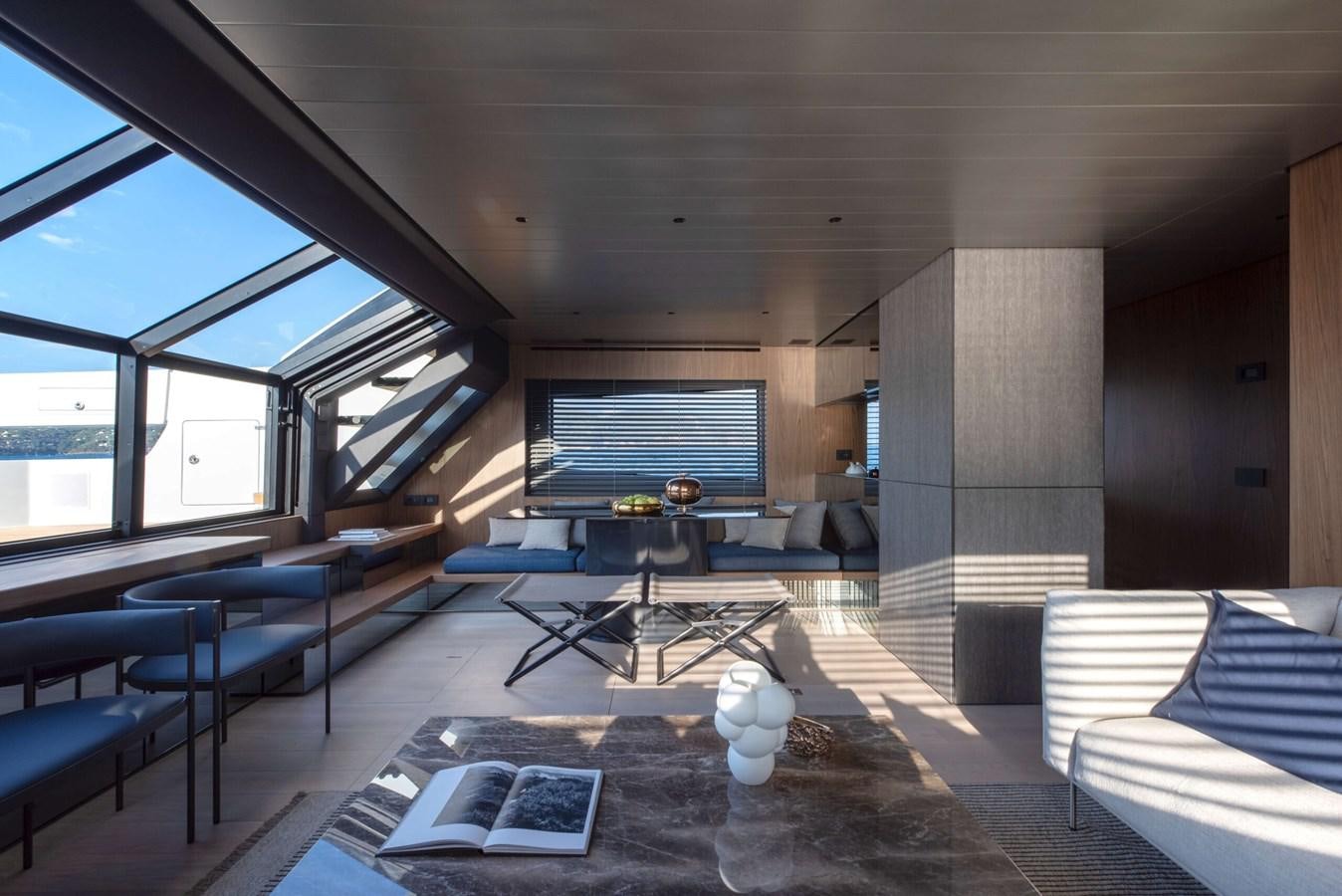 a room with a large window and a table with chairs and a couch aboard ELLEMAR Yacht for Sale