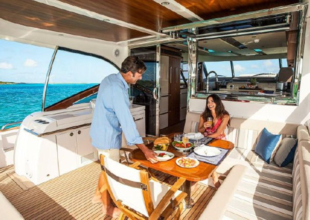 a man and woman eating at a table on a boat aboard 2023 RIVIERA 66 BELIZE DAYBRIDGE Yacht for Sale