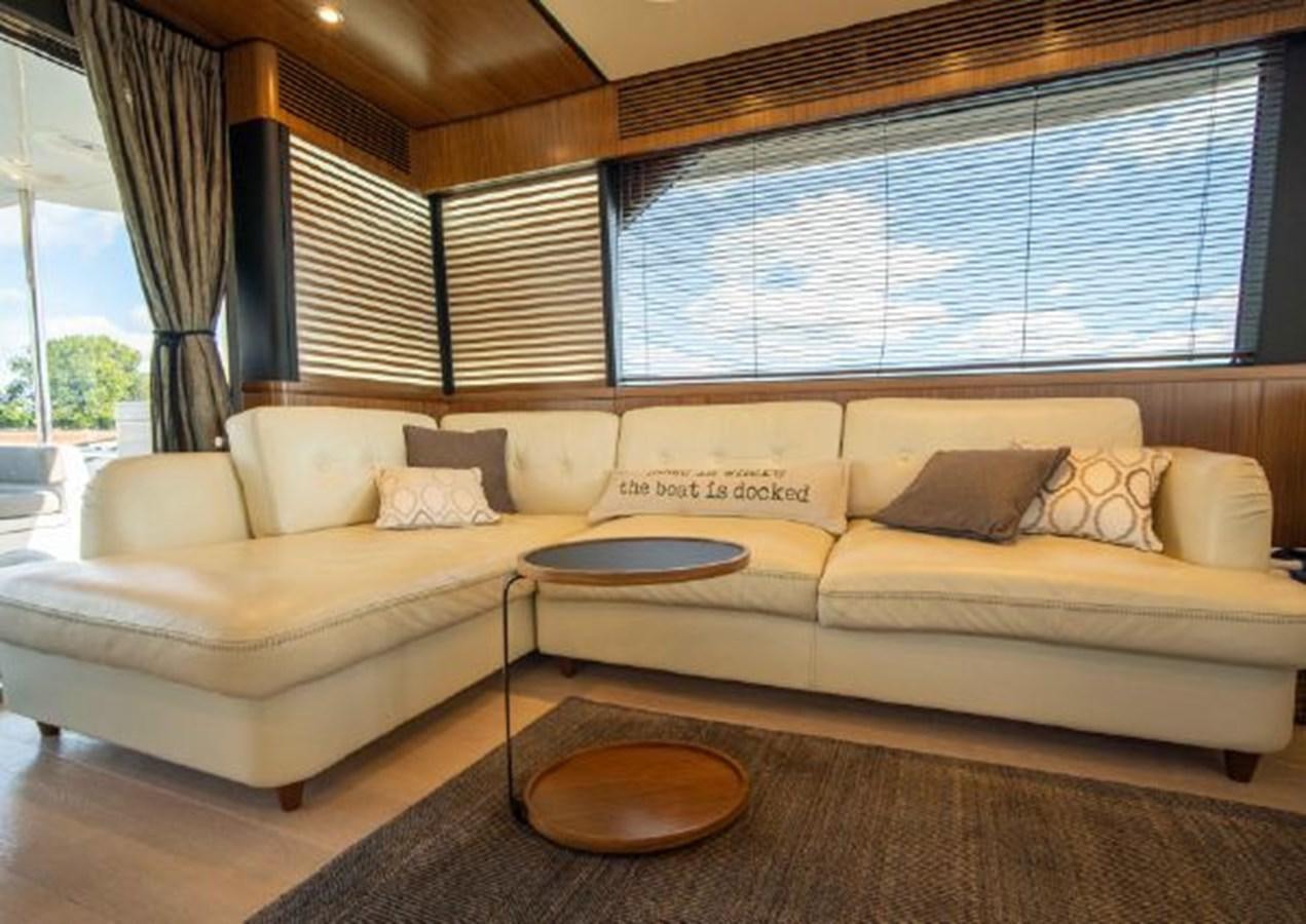 a couch and coffee table in a room with a window aboard 2016 AZIMUT MAGELLANO 66 Yacht for Sale