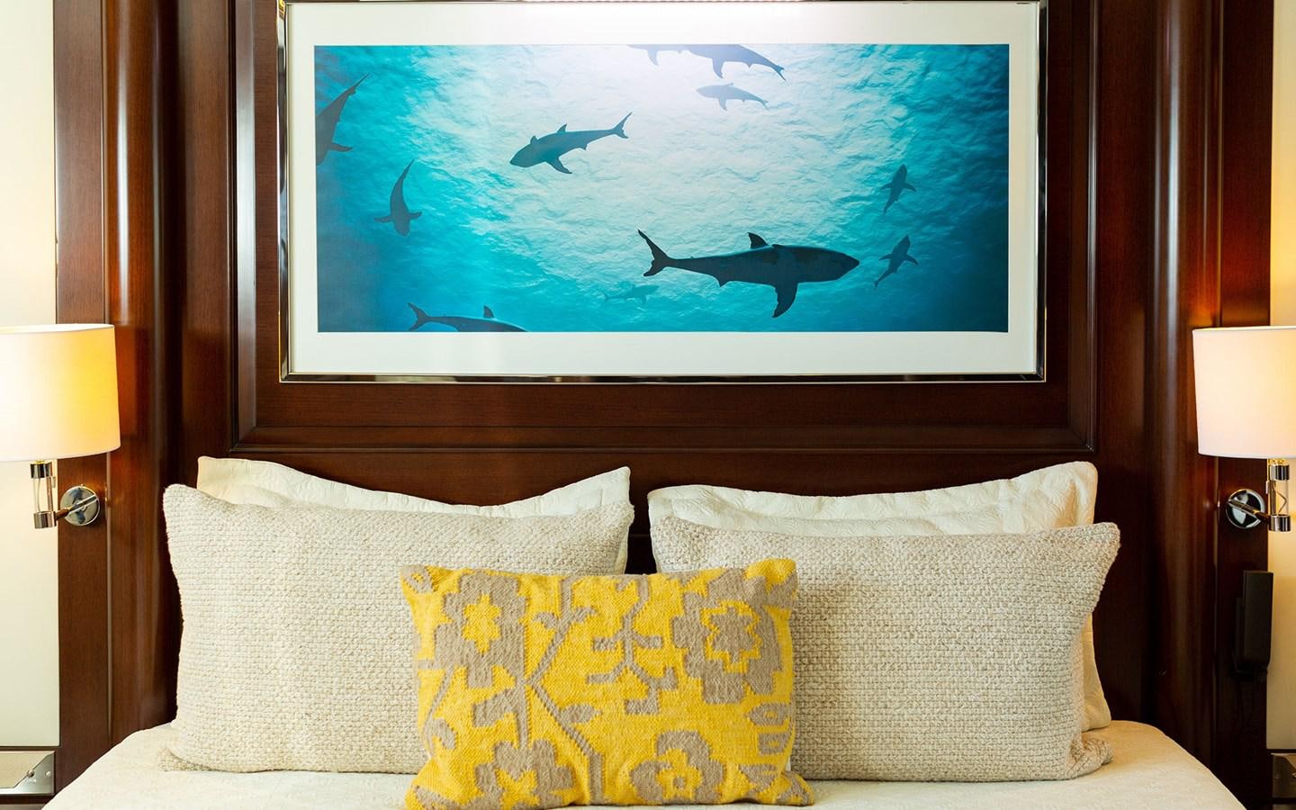 a bed with a painting on the wall aboard MAXIMILIAN MMIV Yacht for Charter