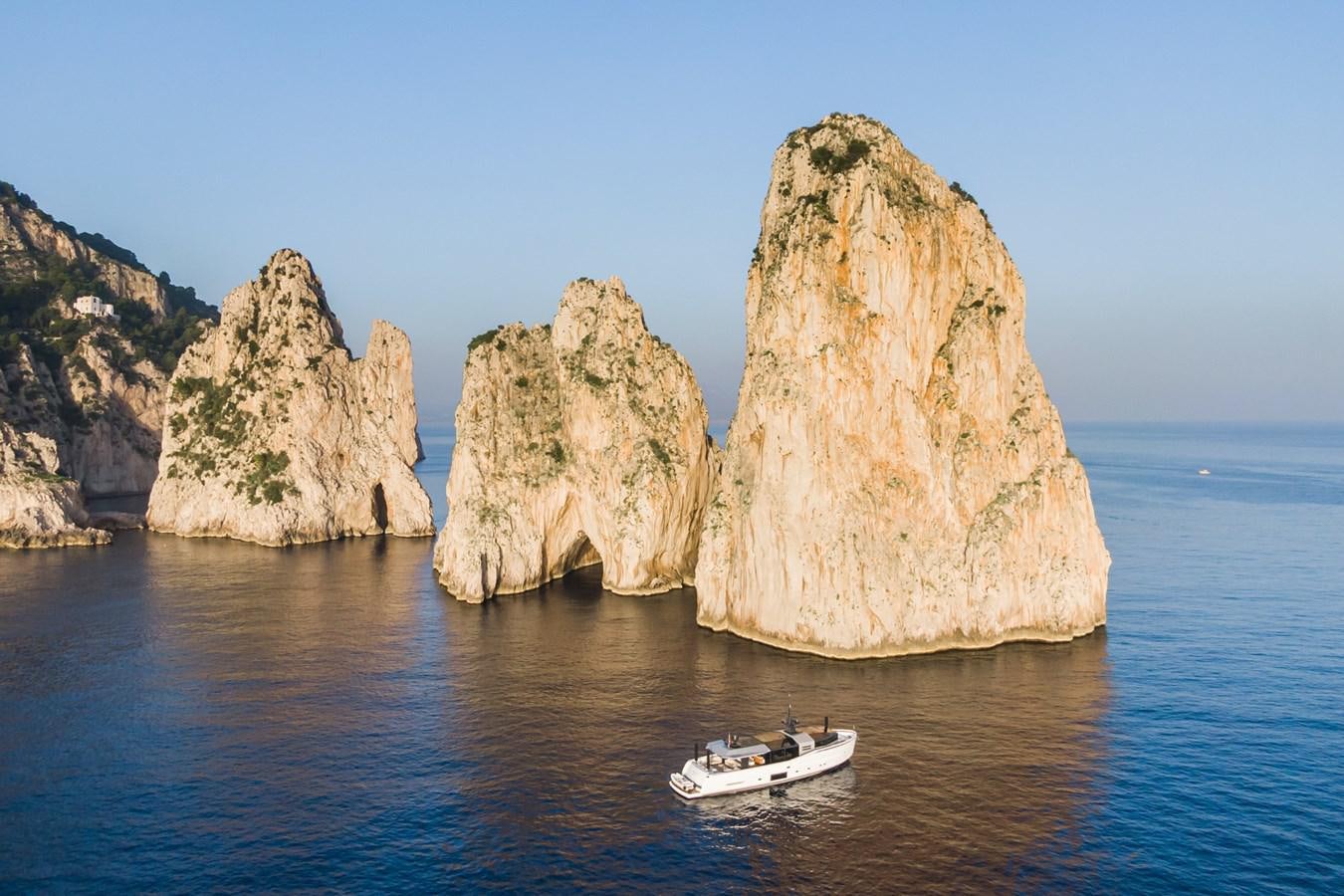 a boat in the water by large rock formations aboard MILU' Yacht for Sale