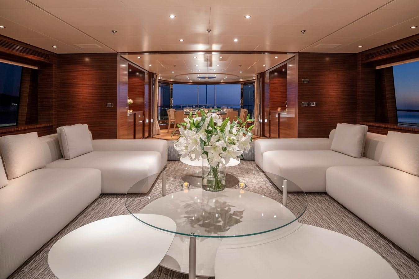 a living room with a table and couches aboard ATLAS Yacht for Sale