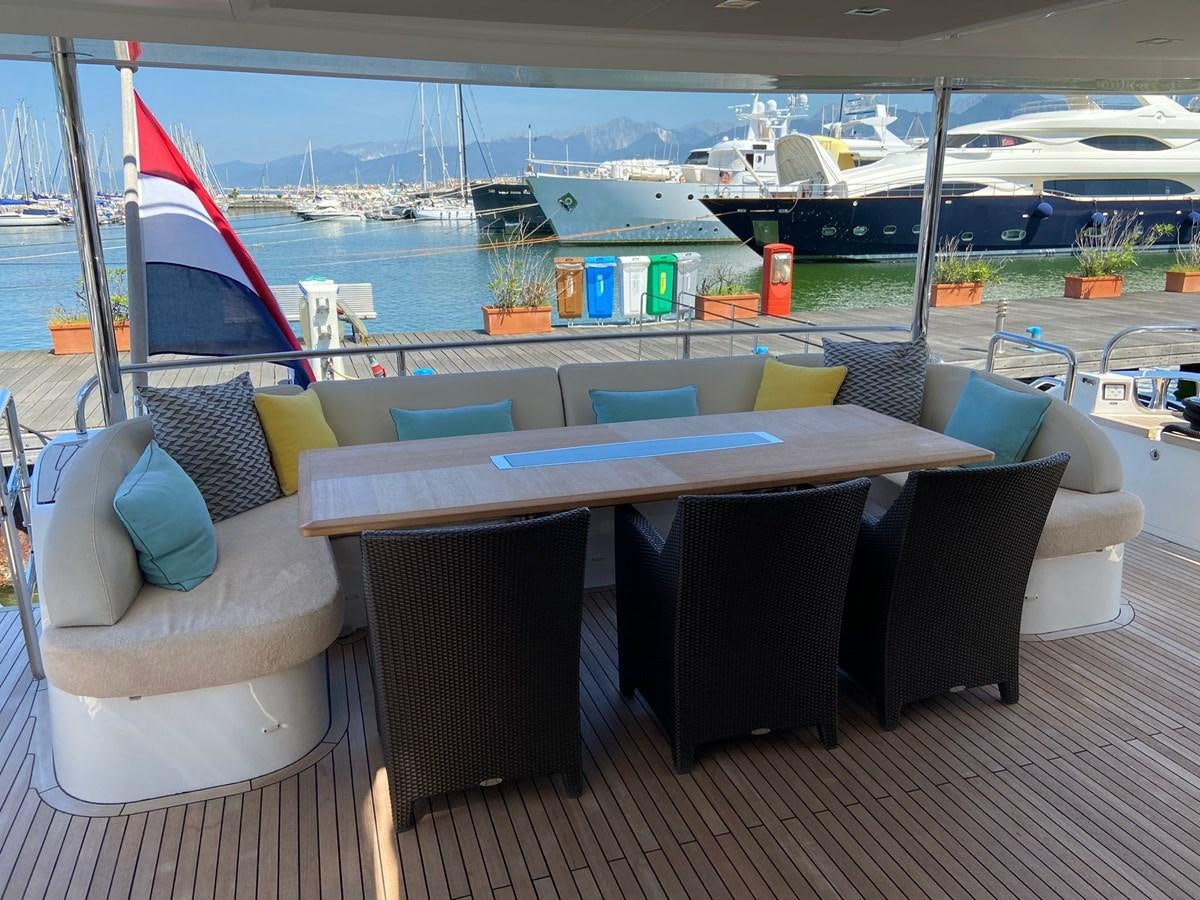 a table and chairs on a deck overlooking a body of water aboard EXPERIENCE Yacht for Sale