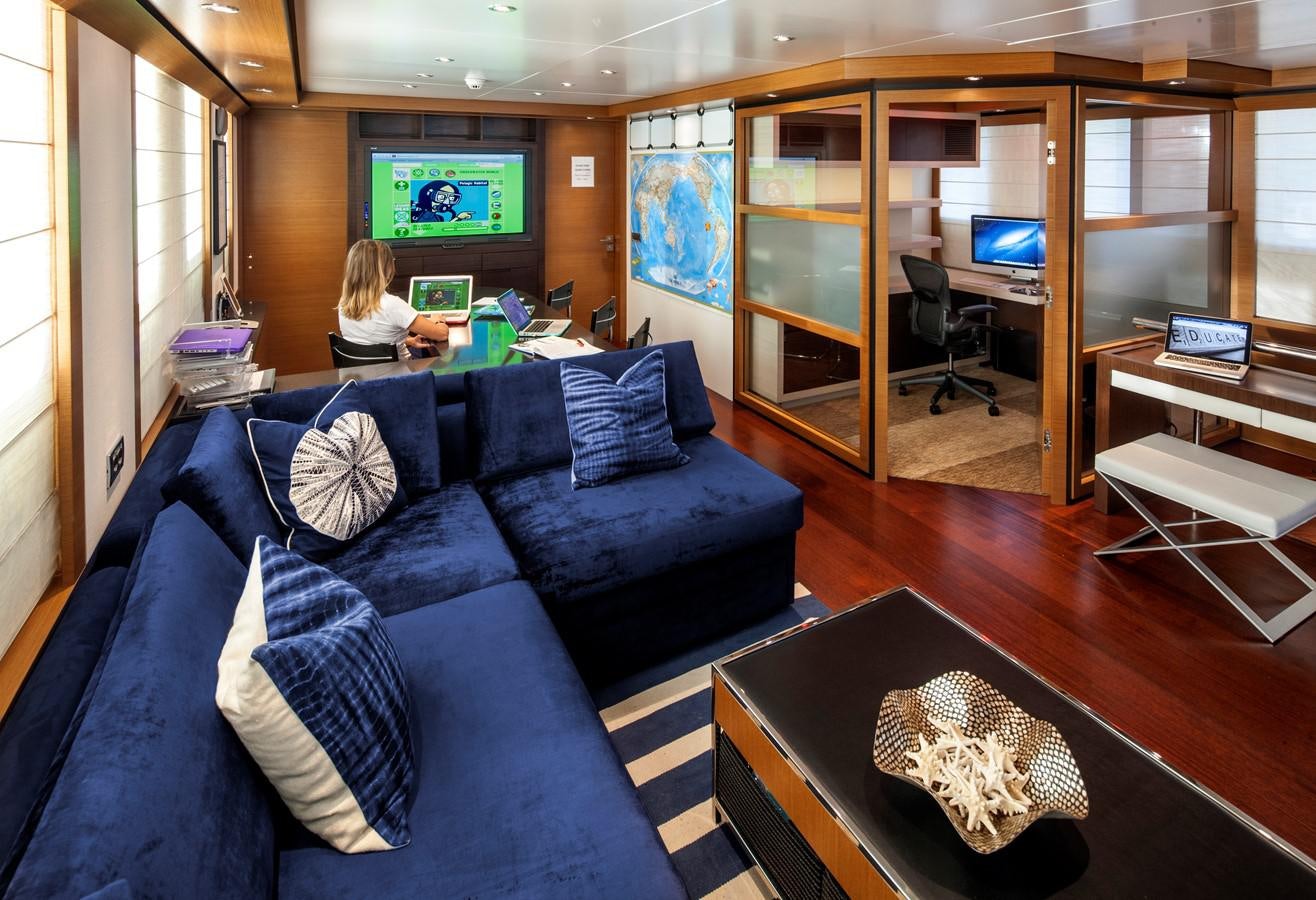 a person sitting on a couch in a living room aboard THE BIG BLUE Yacht for Sale