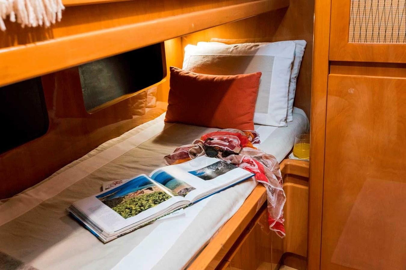 a bed with a book and a pillow on it aboard LOGICA Yacht for Sale