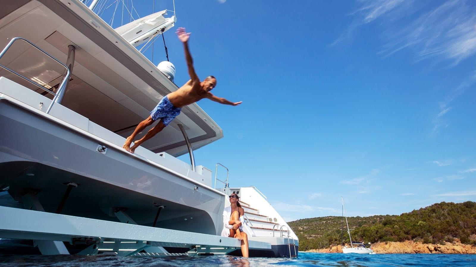 a man and woman jumping off a boat aboard INSPIRANTE Yacht for Sale