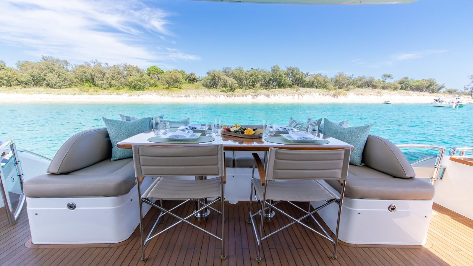 a table and chairs on a deck overlooking a beach aboard SEA WOLF Yacht for Sale