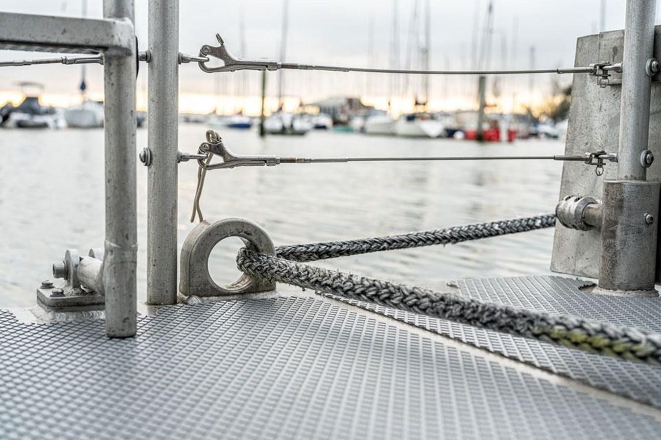 a metal railing with a rope around it and boats in the background aboard COCHISE Yacht for Sale