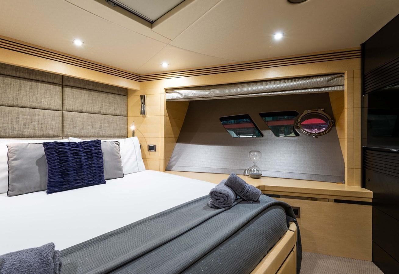 a bed with a white sheet and pillows in a room with a wood wall and a window with aboard CLAVIS Yacht for Sale