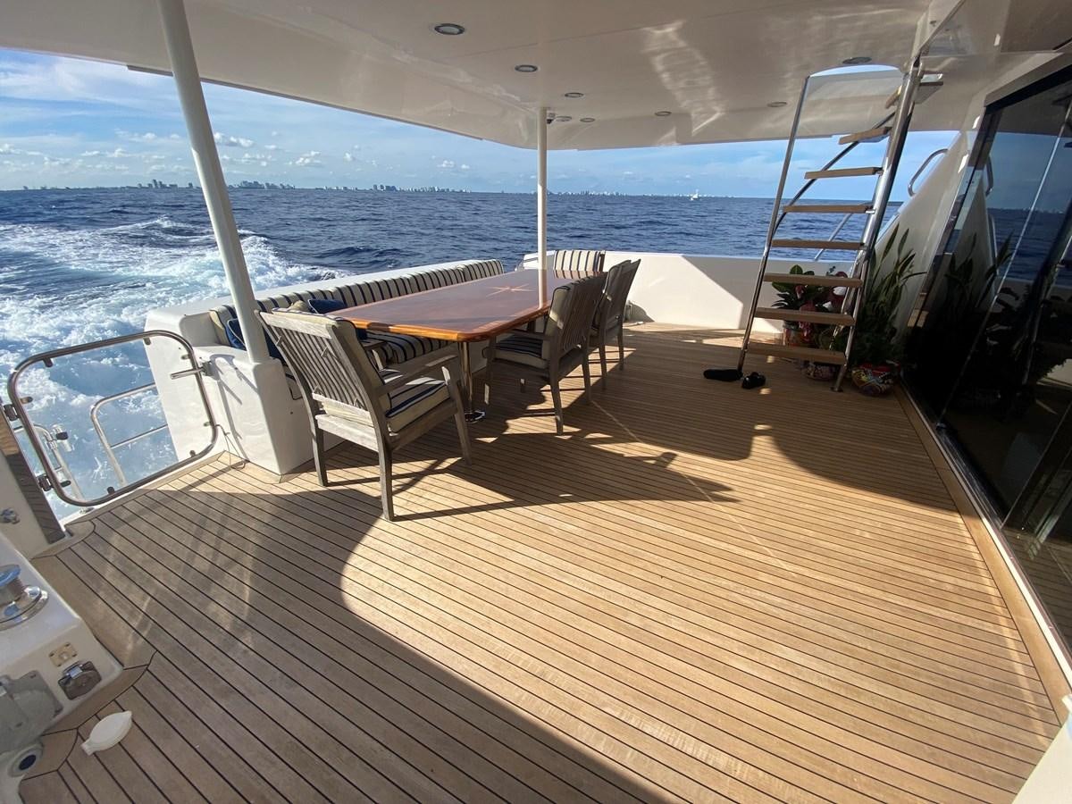 a deck with a table and chairs on it aboard LUCKY AGAIN Yacht for Sale