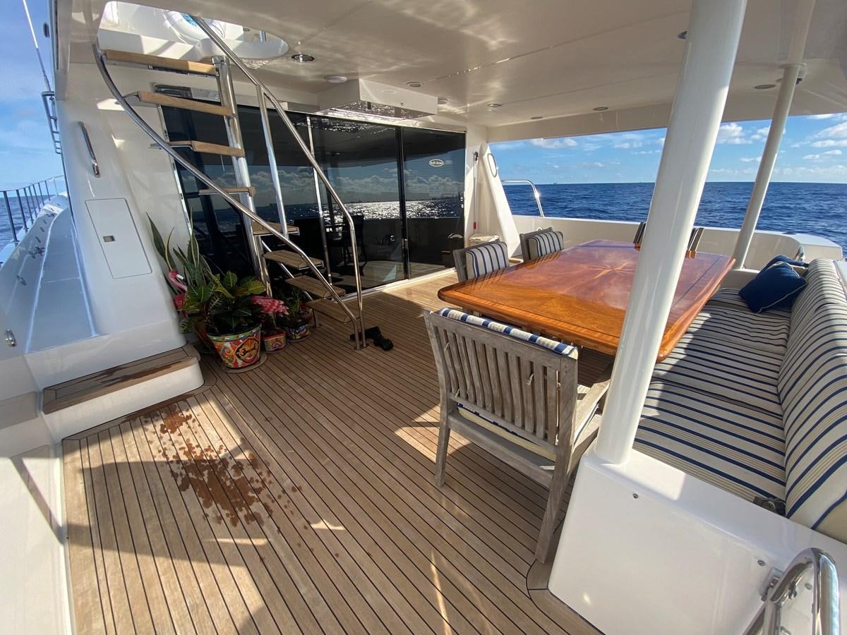 a balcony with a bed and a table on the deck aboard LUCKY AGAIN Yacht for Sale
