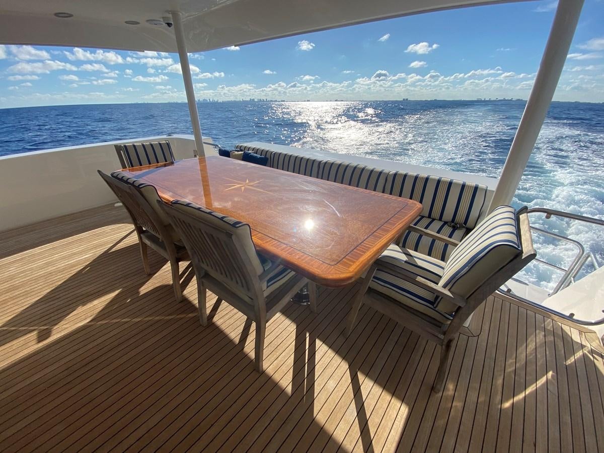 a table and chairs on a deck overlooking a body of water aboard LUCKY AGAIN Yacht for Sale