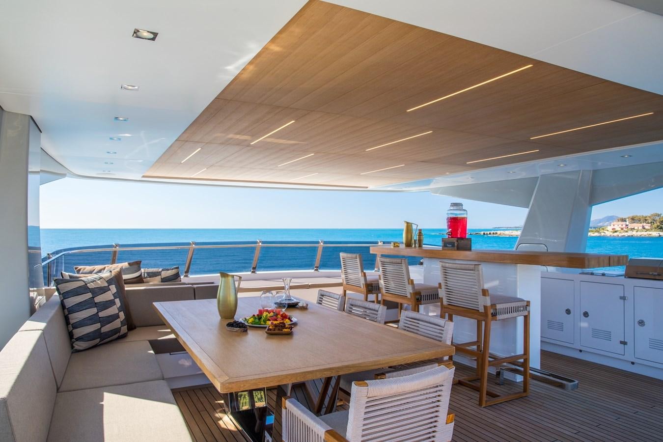 a large open area with a table and chairs and a view of the water aboard SABAI Yacht for Sale