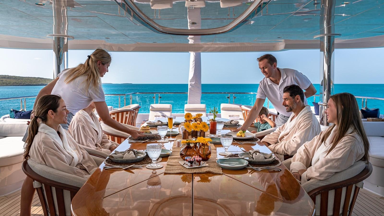 a group of people sitting around a table with food on it aboard STARSHIP Yacht for Charter