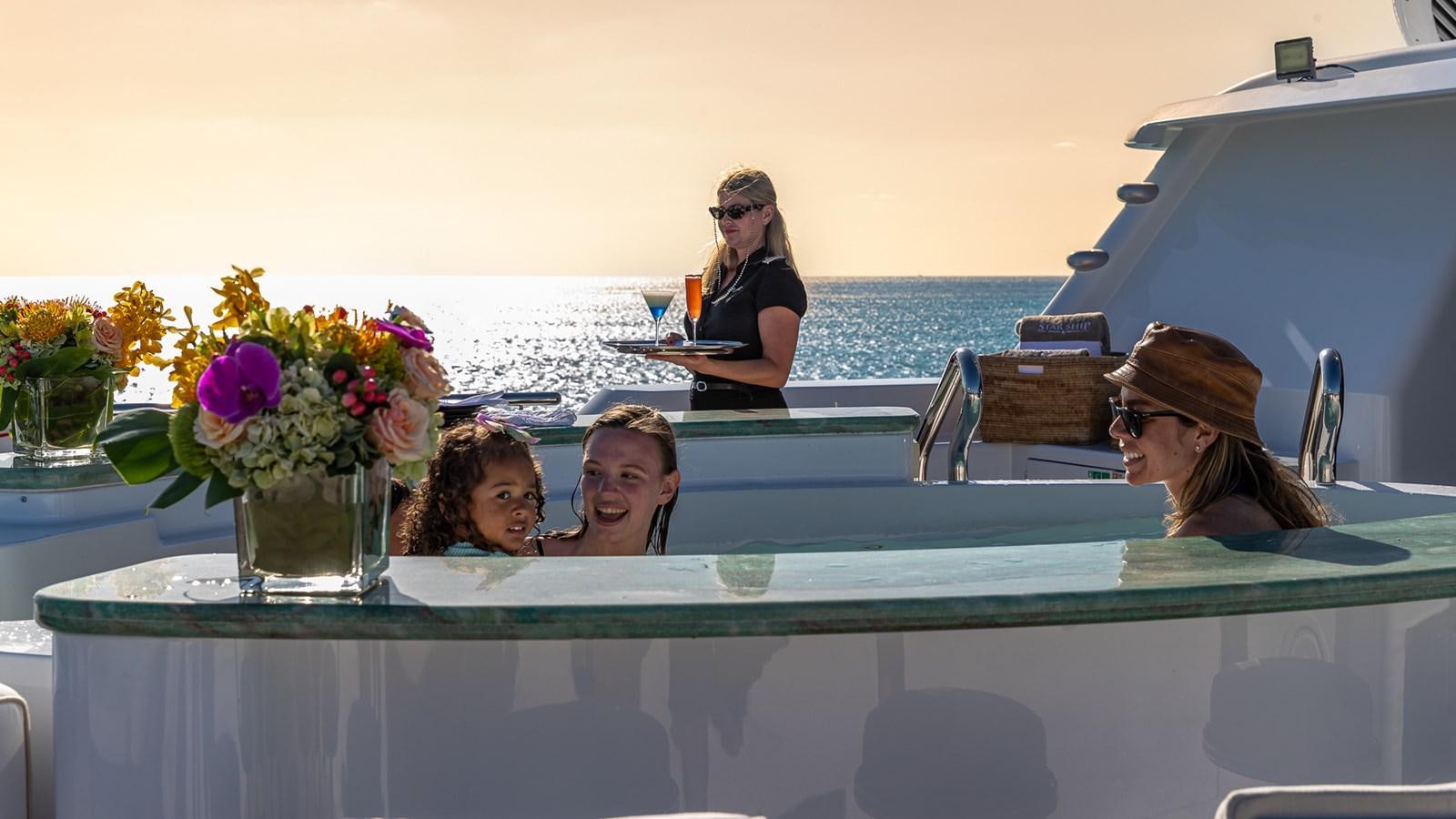 a group of people sitting at a table with flowers in a glass case aboard STARSHIP Yacht for Charter