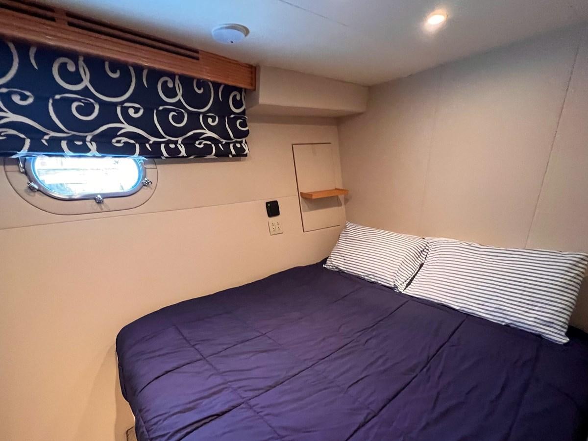 a bed with a blue bedspread and a black and white striped bed spread aboard DESTINI IV Yacht for Sale