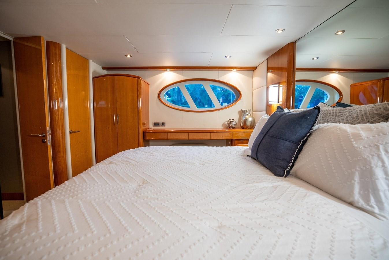 a bed with a white sheet and blue pillows aboard COMPROMISE Yacht for Sale